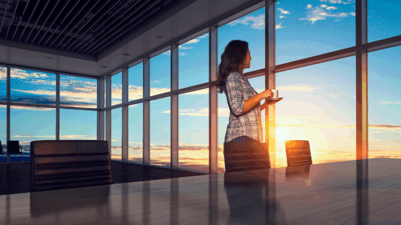 Mujer viendo el amanecer por la ventana